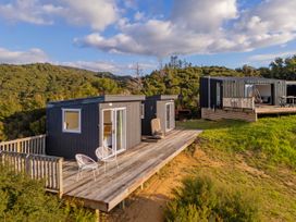 Two cabins with decks and seating overlooking a landscape at Little Tui Ridge - Coromandel