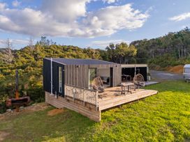 A house with a deck and chairs at Little Tui Ridge - Coromandel Holiday Home, Coromandel