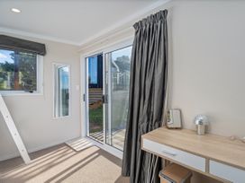 A bedroom with desk and sliding door at Little Tui Ridge - Coromandel Holiday Home Coromandel