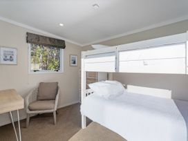 A bedroom with a bunk bed and a desk at Little Tui Ridge - Coromandel Holiday Home, Coromandel