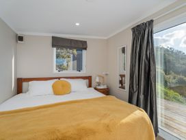 A bedroom with a bed and window at Little Tui Ridge - Coromandel