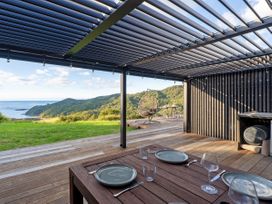 An outdoor patio with a dining table and ocean view at Little Tui Ridge - Coromandel