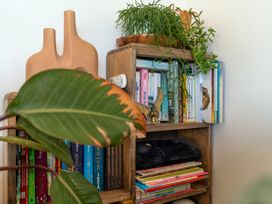 A bookshelf with books and decorative items at Little Tui Ridge - Coromandel Holiday Home, Coromandel