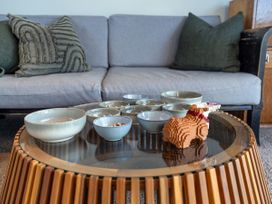 A living room with a sofa, coffee table and decorative objects at Little Tui Ridge - Coromandel