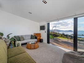 A living room with a sofa, coffee table, and television at Little Tui Ridge - Coromandel