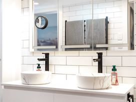 A bathroom with two sinks and mirrors at The Wallnutt Grove - Waihi Beach