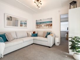 A living room with a sofa and wall art at The Wallnutt Grove - Waihi Beach
