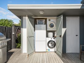 A laundry area with dryer and washing machine at The Wallnutt Grove - Waihi Beach