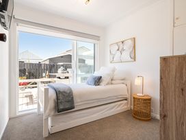 A bedroom with a single bed and bedside table at The Wallnutt Grove - Waihi Beach