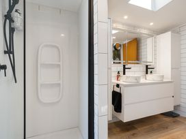 A bathroom with a shower and dual sinks at The Wallnutt Grove - Waihi Beach