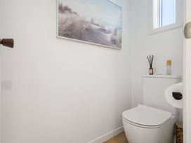 A bathroom with a toilet and wall art at The Wallnutt Grove - Waihi Beach