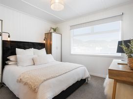 A bedroom with a bed and bedside table at The Wallnutt Grove - Waihi Beach