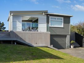 A house with a deck and glass railing at The Wallnutt Grove - Waihi Beach