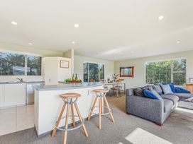 A living room and kitchen area with bar stools at Vineyard View - Blenheim Holiday Home in Blenheim