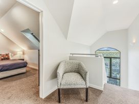 A loft area with a chair and a bed at Vineyard View - Blenheim Holiday Home