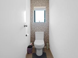 A bathroom with a toilet and window at Fernwood Escape - Tauranga Holiday Retreat Tauranga