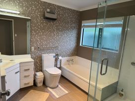A bathroom with a shower, bathtub, toilet, and sink at Fernwood Escape - Tauranga Holiday Retreat
