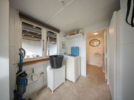 A laundry room with a washing machine and a laundry basket at Dragon Fly Cottage - Te Anau