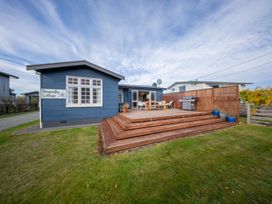 A cottage with a deck and outdoor furniture at Dragon Fly Cottage - Te Anau