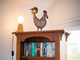 A bookshelf with a wire chicken decoration and a lamp at Dragon Fly Cottage - Te Anau Holiday Home Te Anau