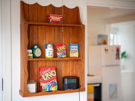 A shelf displaying games and a clock at Dragon Fly Cottage - Te Anau
