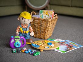 A playroom with toys including a figure, camera, cars, and books at Dragon Fly Cottage - Te Anau Holiday Home