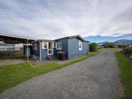 A blue house with a gravel driveway at Dragon Fly Cottage - Te Anau Holiday Home Te Anau