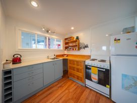 A kitchen with stove, refrigerator, and sink at Dragon Fly Cottage - Te Anau