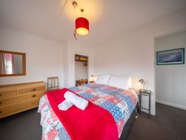 A bedroom with a bed, dresser, and mirror at Dragon Fly Cottage - Te Anau