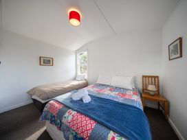 A bedroom with two beds and a bedside table at Dragon Fly Cottage - Te Anau Holiday Home