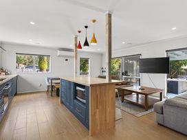 A kitchen with a counter island and stools at Ruakaka Holiday Home in Ruakaka