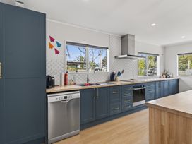 A kitchen with blue cabinetry and stainless steel appliances at Ruakaka Holiday Home in Ruakaka