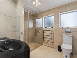 A bathroom featuring a shower, sink, toilet and heated towel rail at Ruakaka Holiday Home Ruakaka