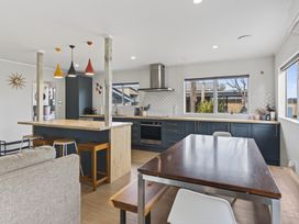 A kitchen with a dining table and cooking appliances at Ruakaka Holiday Home in Ruakaka