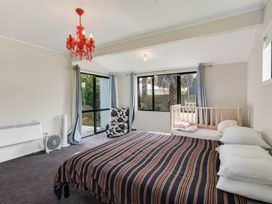 A bedroom with a bed and a crib at Ruakaka Holiday Home in Ruakaka