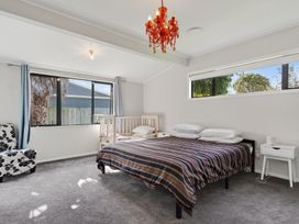 A bedroom with a bed and a crib at Ruakaka Holiday Home in Ruakaka