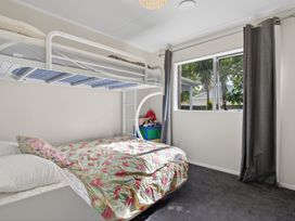 A bedroom with a bunk bed and storage area at Ruakaka Holiday Home in Ruakaka
