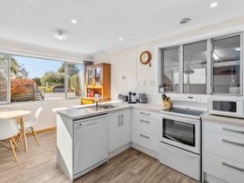 A kitchen with appliances and dining area at Get Away By The Green - Cromwell