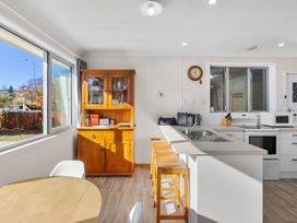 A kitchen with a wooden cabinet and round table at Get Away By The Green - Cromwell
