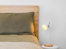 A bed with a pillow and a lamp on a bedside table at Te Ohu - Wanaka Holiday Home in Wanaka