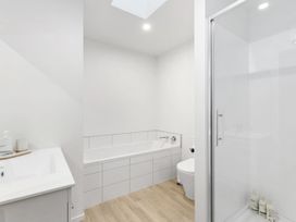 A bathroom featuring a bathtub, shower, toilet, and sink at Te Ohu - Wanaka Holiday Home in Wanaka