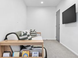 A snug room with a sofa and television at Te Ohu - Wanaka Holiday Home in Wanaka