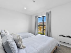 A bedroom with two beds, window, and curtain at Te Ohu - Wanaka Holiday Home in Wanaka