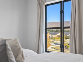 A bedroom with a window view of houses and mountains at Te Ohu - Wanaka Holiday Home in Wanaka