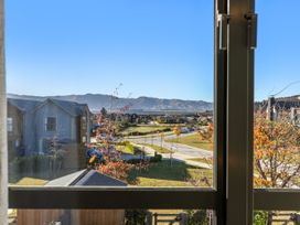 A view from a window showing mountains and buildings at Te Ohu - Wanaka Holiday Home Wanaka
