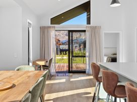 A dining room with a table and chairs looking out through a sliding door at Cromwell Holiday Home in Cromwell