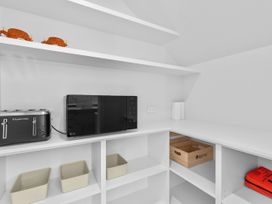A kitchen storage area with a microwave, toaster, and shelves at Cromwell Holiday Home in Cromwell