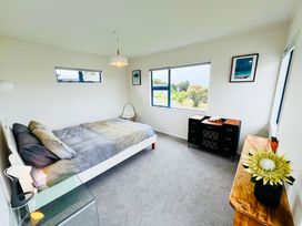 A bedroom with a bed and furniture at La Maison Bleu - Mangawhai Heads Holiday Home Mangawhai
