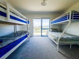 A bedroom with bunk beds and a sliding door at La Maison Bleu - Mangawhai Heads Holiday Home, Mangawhai