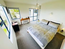 A bedroom with a bed and a table at La Maison Bleu - Mangawhai Heads Holiday Home, Mangawhai
